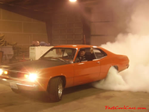 1970 Plymouth Duster doing huge burnout in a garage.